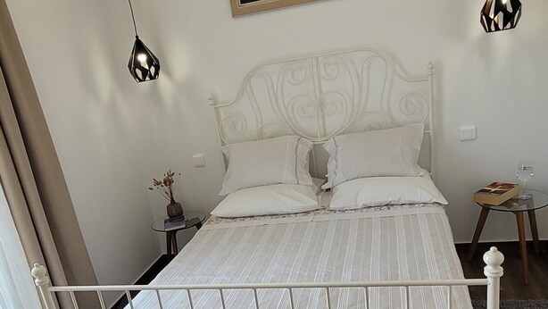 A bedroom with a white metal bed frame, a painting above the bed, and two pendant lights. - Country House for Holidays with Wi-Fi (Ribeira)