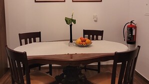 A dining area with a round table, four chairs, a vase with flowers, and two framed pictures on the wall. - Country House for Holidays with Wi-Fi (Ribeira)