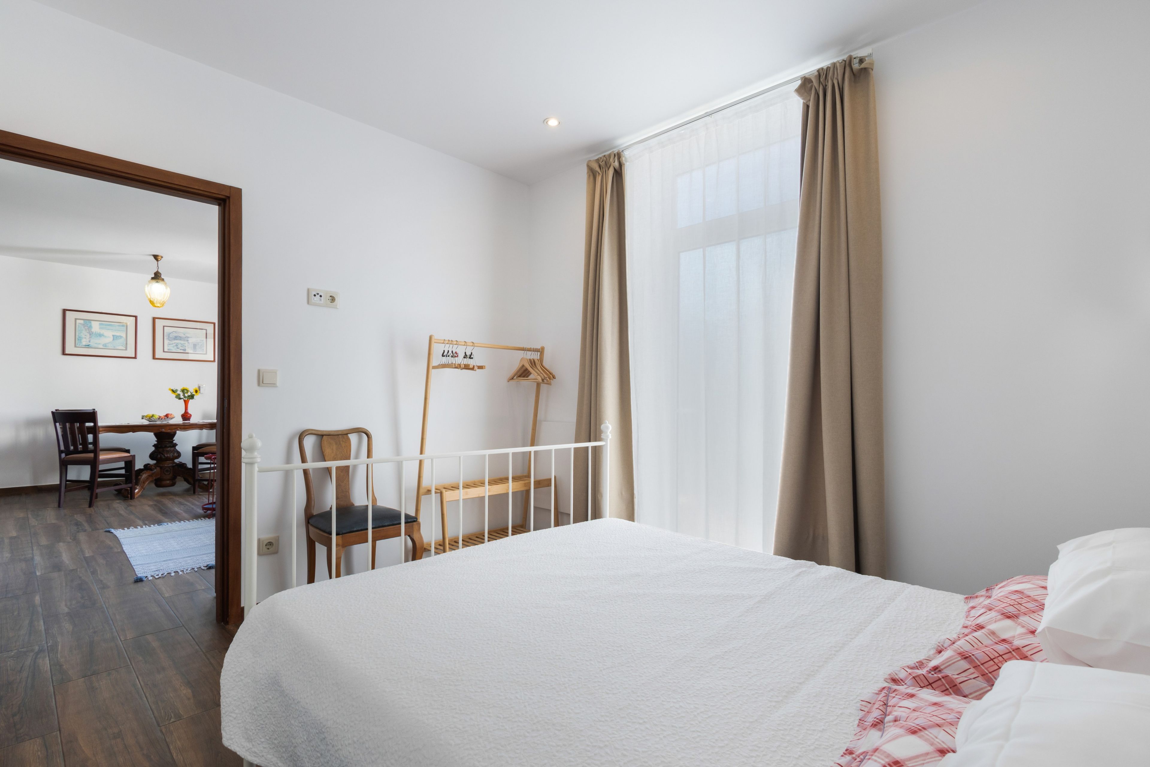 Een slaapkamer met een bed, een stoel, een bureau en een raam met gordijnen.