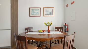 Un coin repas avec une table en bois, des chaises, un vase de fleurs et des tableaux encadrés accrochés au mur.