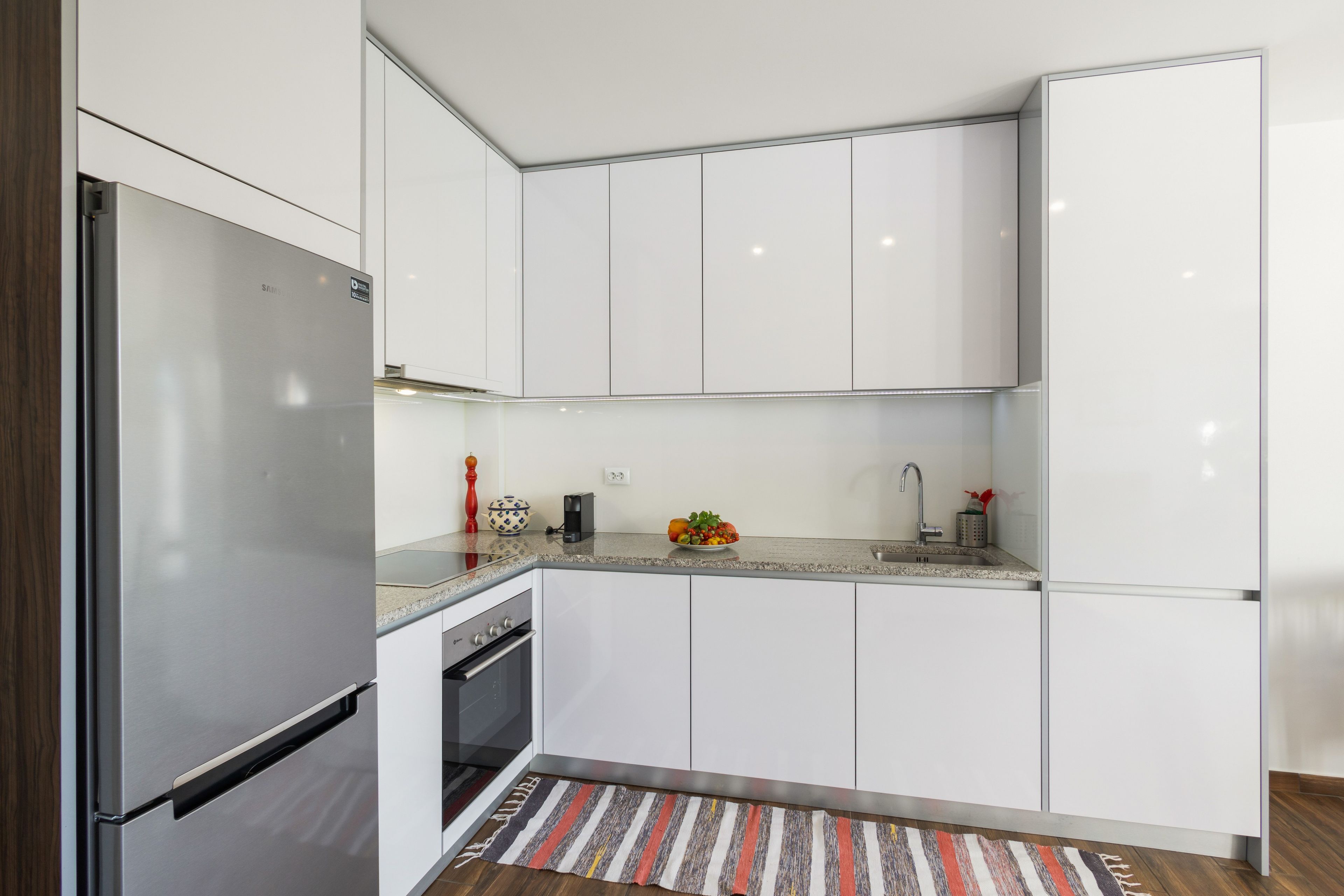 Een moderne keuken met witte kasten, roestvrijstalen apparatuur en een granieten aanrecht.