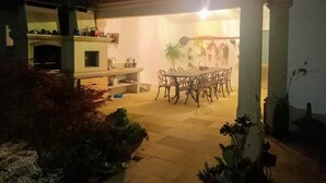 An outdoor patio area with a dining table and chairs, surrounded by potted plants and a fireplace. - Country House for Holidays with Wi-Fi (Ribeira)