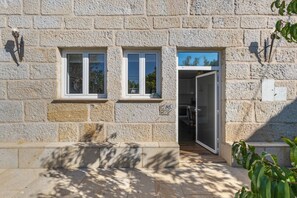 Un bâtiment en pierre doté de deux fenêtres et d’une porte donnant sur un espace intérieur.