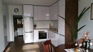 A modern kitchen with white cabinetry, a built-in oven, and a dining area with a wooden table and chairs. - Country House for Holidays with Wi-Fi (Ribeira)