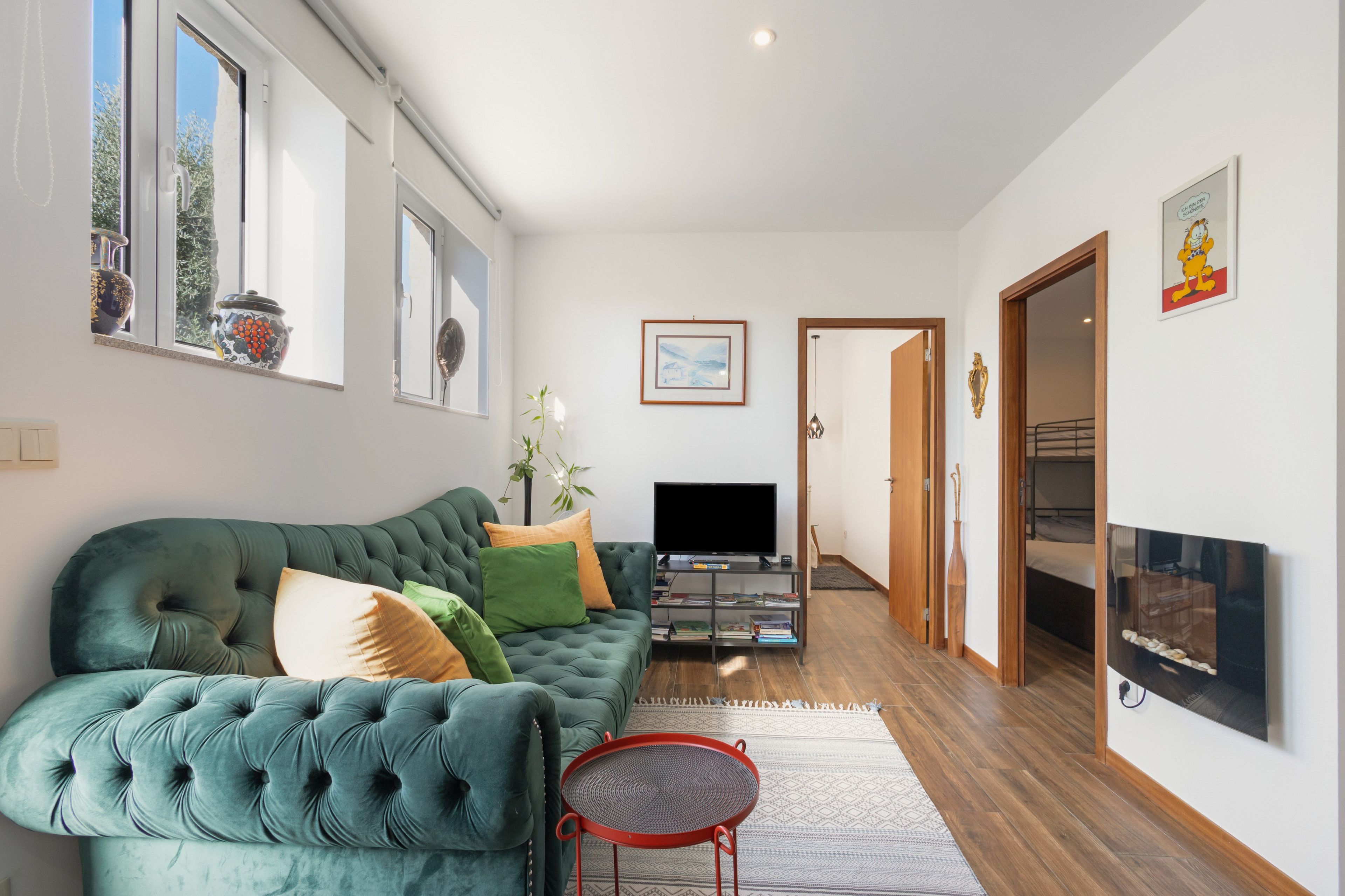 Ein modernes Wohnzimmer mit einem grünen Sofa, einem Flachbildfernseher und einem roten Sessel.