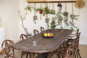 Une table à manger avec un plateau en métal décoratif, entourée de chaises élégantes, et une assiette de fruits.