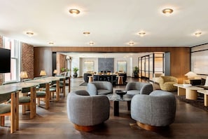 A modern hotel lobby with a long dining table, several sofas, and a fireplace. - Arlo DC | Junior Suite | Near National Mall | Seasonal Pool Access (Washington)