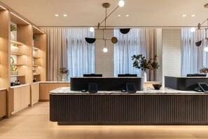 A modern reception area with a central counter, a digital screen, and a plant.