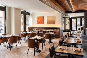 A restaurant with a modern interior, featuring a mix of booths and tables, a herringbone floor pattern, and large windows allowing natural light. - Arlo DC | King | Near National Mall | Rooftop Bar (Washington)