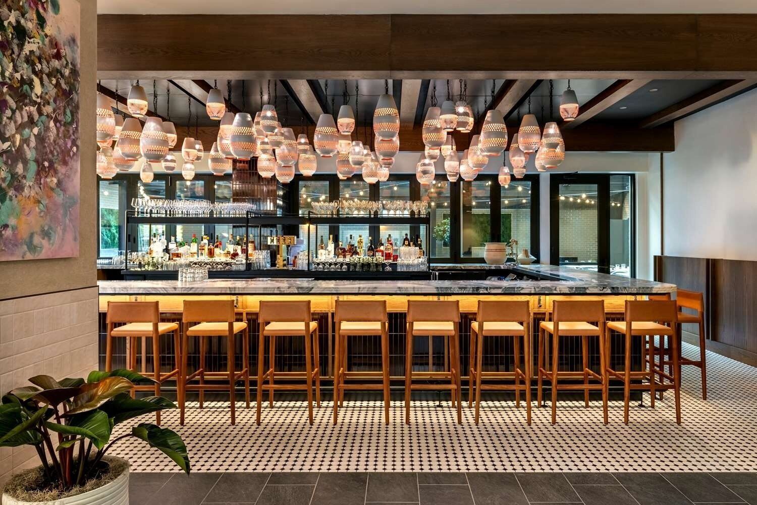 Eine Bar mit mehreren hängenden Lampen, einer Theke und einigen Barhocker.