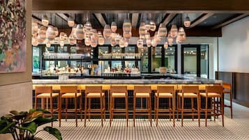 Eine Bar mit mehreren hängenden Lampen, einer Theke und einigen Barhocker.