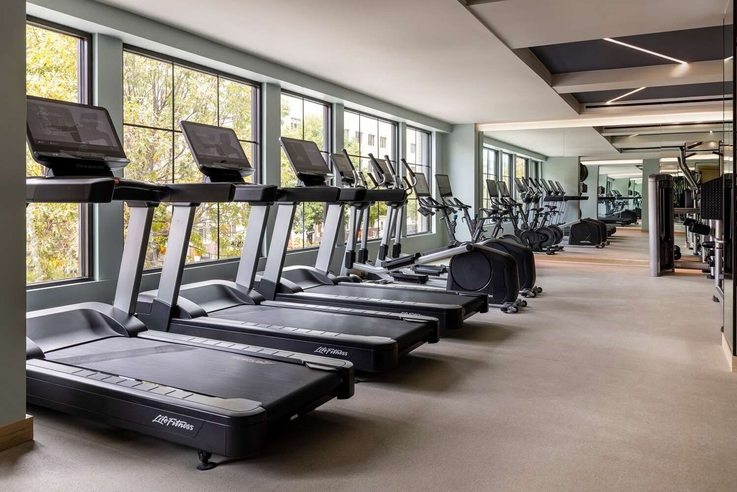 Ein Fitnessstudio mit mehreren Laufbändern, Ergometer und weiteren Trainingsgeräten.