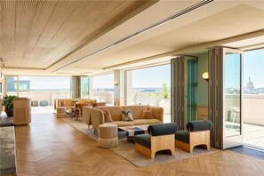 A spacious living area with a high ceiling, large windows, and a view of the cityscape.
