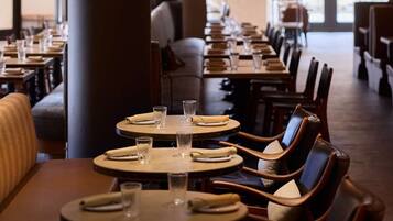 Ein Restaurant mit runden Tischen, Stühlen und hängenden Pendelleuchten.