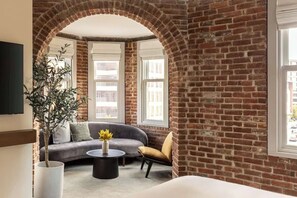 A room with a brick wall, a sofa, a chair, a coffee table, and a plant.