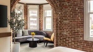 Une pièce avec un mur en briques, un canapé, un fauteuil, une table basse et une plante.