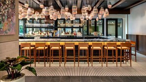 Un espace bar doté de plusieurs luminaires suspendus, d’un comptoir et de plusieurs tabourets de bar.