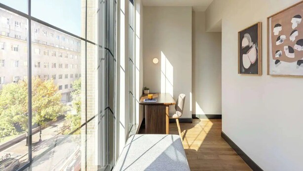 Un intérieur moderne avec de grandes fenêtres, un plancher en bois et des œuvres d’art accrochées aux murs.