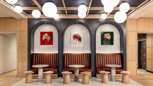 Un intérieur moderne avec des lambris en bois, des tables surmontées de marbre et des œuvres d’art accrochées aux murs.