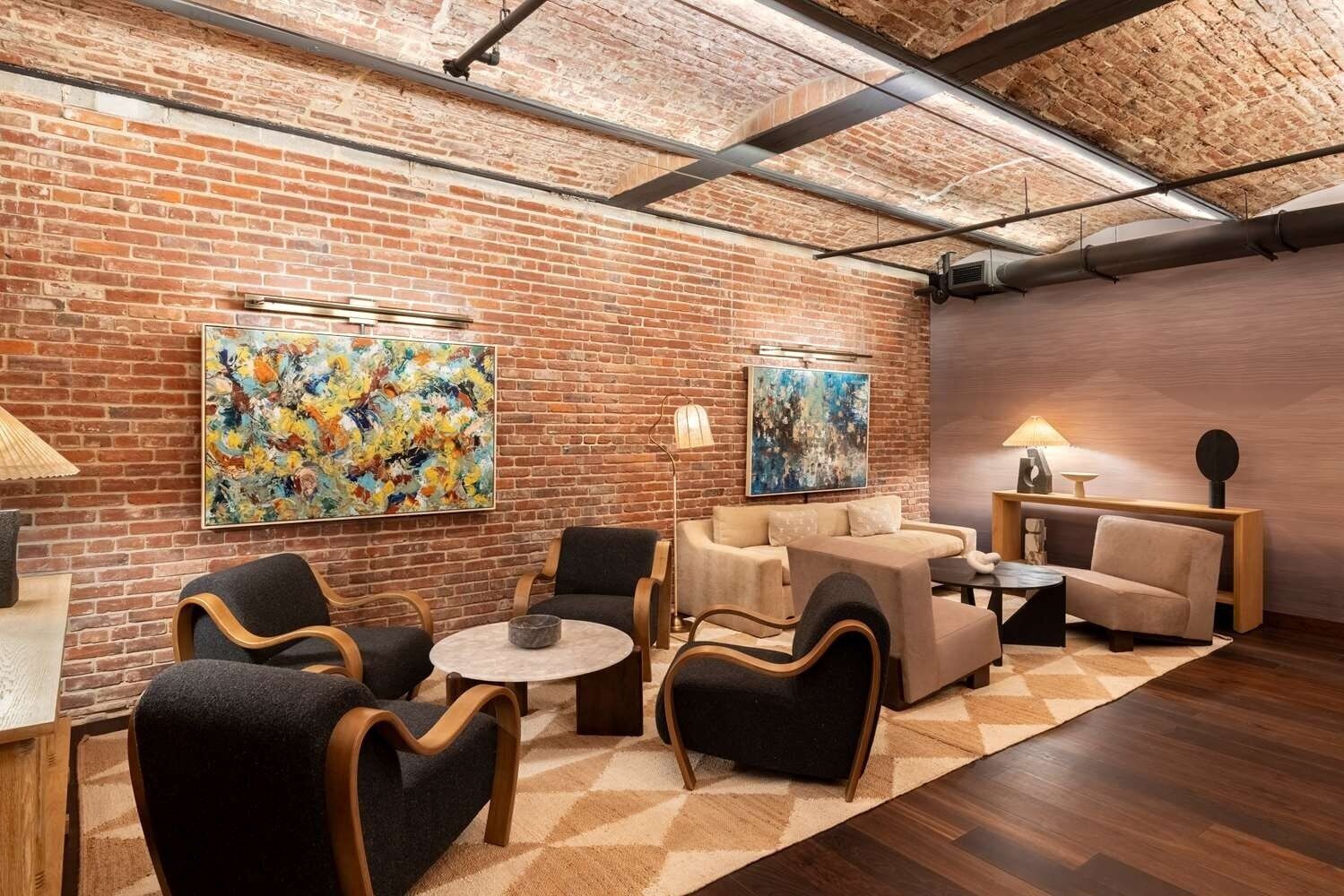 Eine moderne Lounge mit Backsteinwänden, abstrakter Kunst und zeitgemäßen Möbeln.