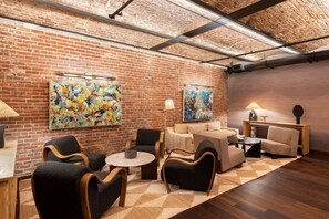 Un salon moderne avec des murs en briques, des œuvres d’art abstraites et des meubles contemporains.
