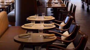 Un restaurant avec des tables rondes, des chaises et des lampes suspendues.