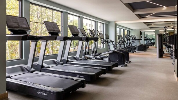 Une salle de sport équipée de plusieurs tapis de course, de vélos d’exercice et d’autres appareils de musculation.