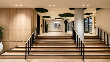 Eine Treppe mit Holzdielen und schwarzen Geländern, die zu einer Zwischenebene mit einem Blumentopf und Kunstwerken führt.