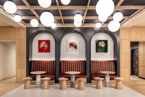 A modern interior with wooden paneling, marble-topped tables, and wall-mounted artwork.