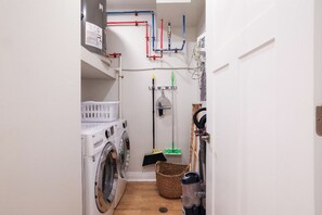 Een wasserette met een wasmachine, een droger, een bezem en een stofzuiger.