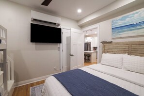 Ein Schlafzimmer mit einem Bett, einem Fernseher, einem Deckenventilator und einem Bild an der Wand.
