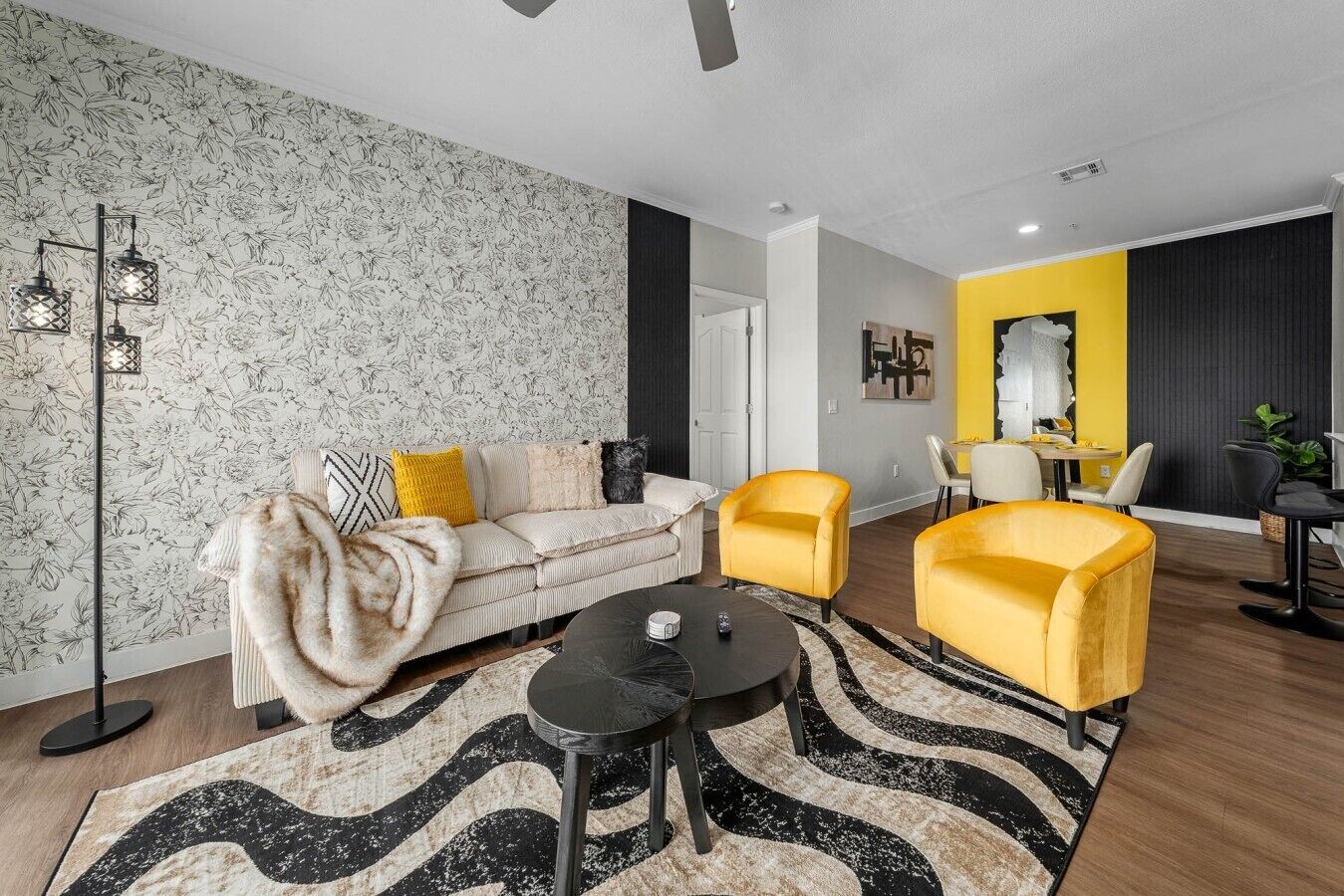 A modern living room with a sofa, two yellow armchairs, a coffee table, and a patterned rug.