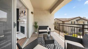 Ein Balkon mit Korbmöbeln, einem Blumentopf und einem Kamin.