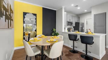 A modern kitchen with white cabinets, a central island, and a dining area with a round table and chairs.