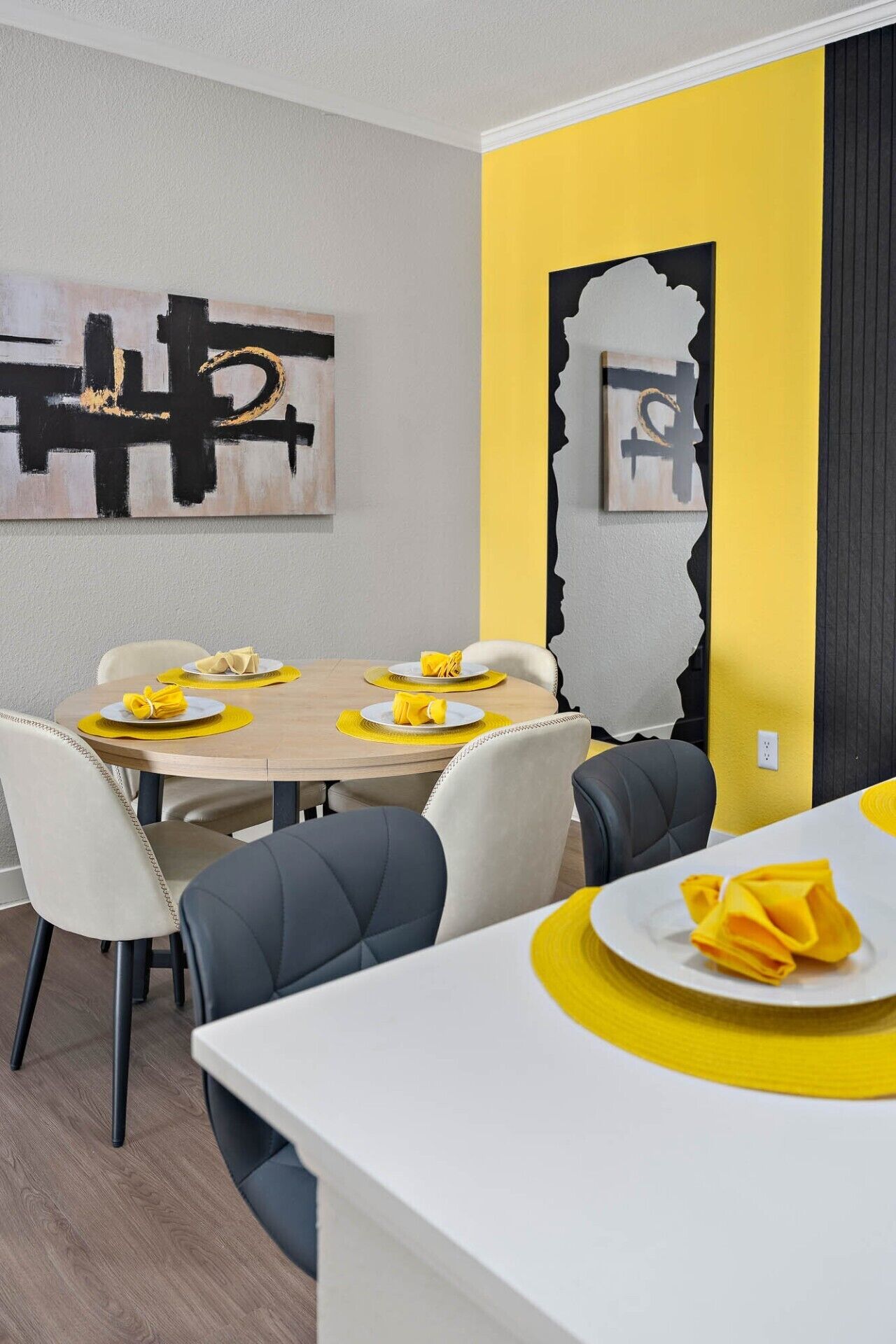 A dining area with a table set for four, chairs, and a wall with abstract art.