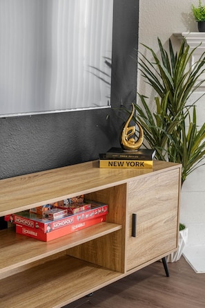 Ein Holzerichteil mit einem darüber angebrachten Fernseher, einem goldenen Dekorationsobjekt und einer Pflanze daneben.
