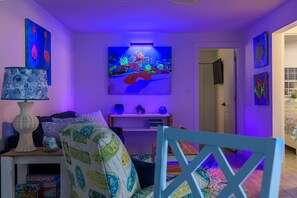 Ein Wohnzimmer mit Fernseher, einer Couch, einem Couchtisch und einem Sessel.