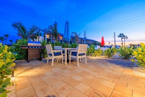 Un patio al aire libre con una parrilla, asientos y plantas.