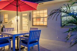 A patio with a table and chairs, a red umbrella, and a house number 2655. - Coastal Dunedin Suite Near Beaches (Dunedin)