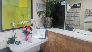 A reception desk with a calendar for 2026, a plant, and a vase with flowers. - Del Rancho Motel (Portland)