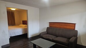 A small, compact room with a bed, a sofa, and a small table. - Del Rancho Motel (Portland)