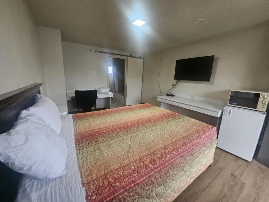A hotel room with a bed, a desk, a television, and a microwave.