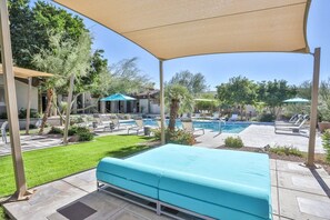 Zona junto a la piscina con espacio de descanso cubierto, piscina y sillas de descanso.
