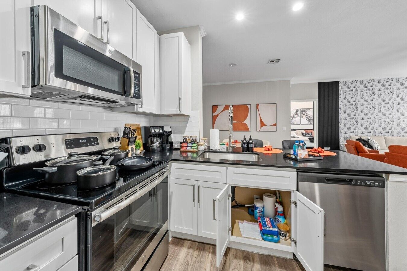 A modern kitchen with stainless steel appliances, white cabinetry, and a built-in dishwasher.