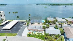 A coastal hotel with a parking lot, a pool area, and a view of the sea. - Colorful Coastal Retreat Near Honeymoon Island Beaches (Dunedin)
