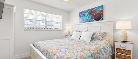 A bedroom with a bed, a nightstand, a lamp, a window with blinds, and a ceiling light fixture.