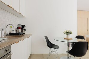 A compact kitchen with a sink, coffee maker, and modern chairs. - Stylish bright apartment with private garden (London)