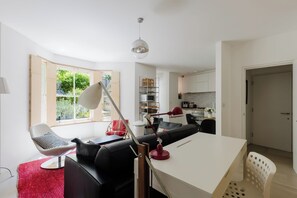 Ein modernes Wohnzimmer mit einer Couch, einem Esstisch und einer Küche im Hintergrund.