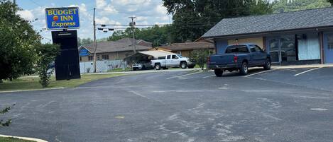 A parking lot with a Budget Inn Express sign, a building with a garage, and a blue pickup truck.