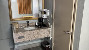 A bathroom with a sink, mirror, towel rack, and a coffee maker.